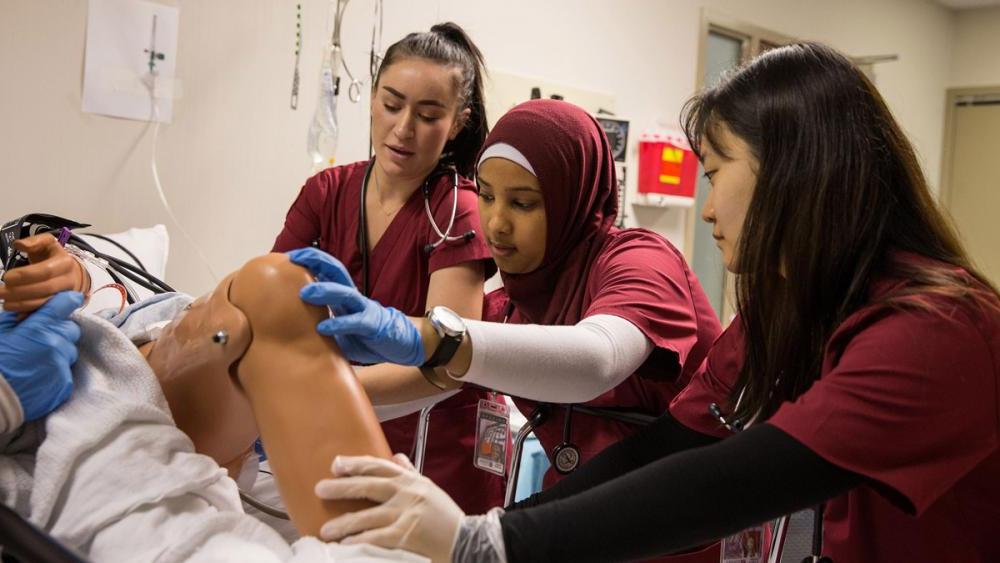 Temple nursing students conducting simulation on a mannequin in training lab.