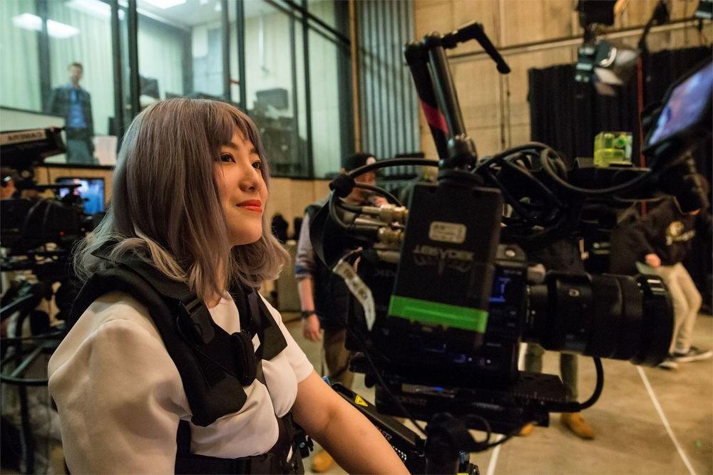 一位电影专业的学生坐在校园电影制片厂的电影设备中间.