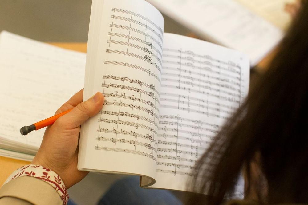 A student reads a book of sheet music.