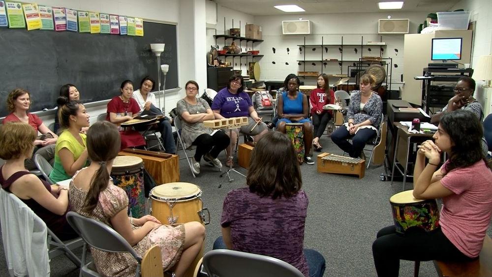 爵士乐的学生在教室里围成一圈坐着，面前放着各种各样的打击乐器.
